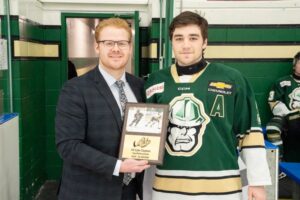 (Left to right) Oilers assistant coach Brody Hailwood standing with Cyle Clayton as he accepts the Top Defenceman award. (Chad Goddard/Okotoks Oilers)