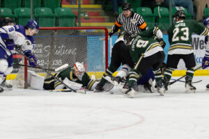 Justin Giguère reaching for a loose puck with chaos in front of his net. (Chad Goddard/Okotoks Oilers)